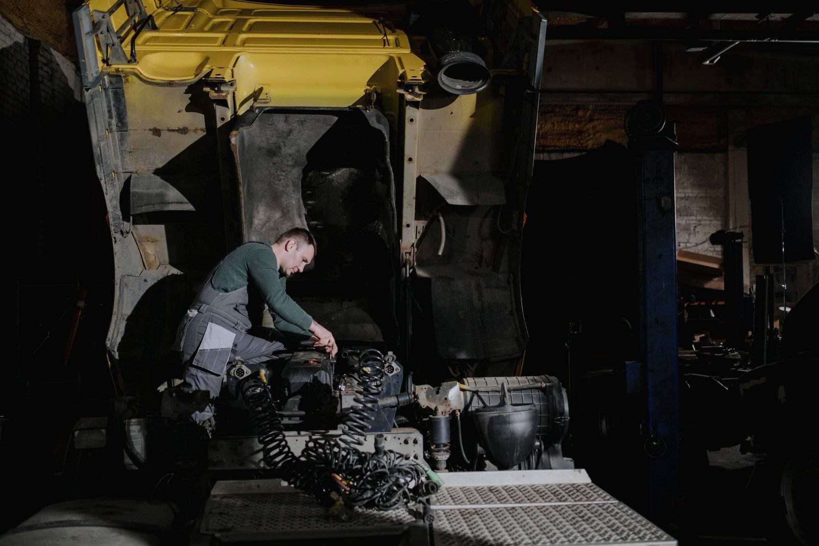 A technician working on coiled air lines behind a truck cab