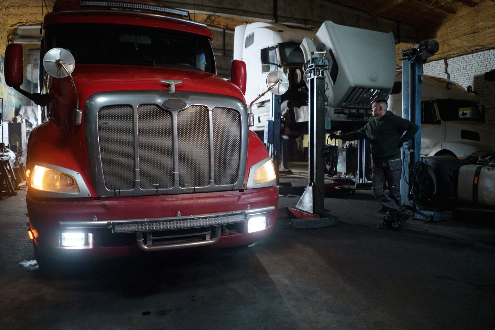Wide view of a repair shop floor with a tractor unit and a raised cab
