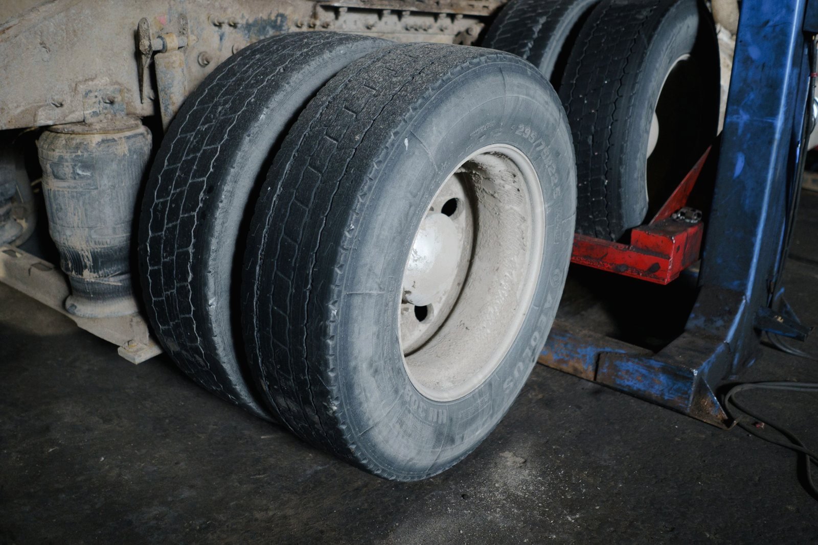 Dual wheels on a trailer axle with a jack positioned under the frame