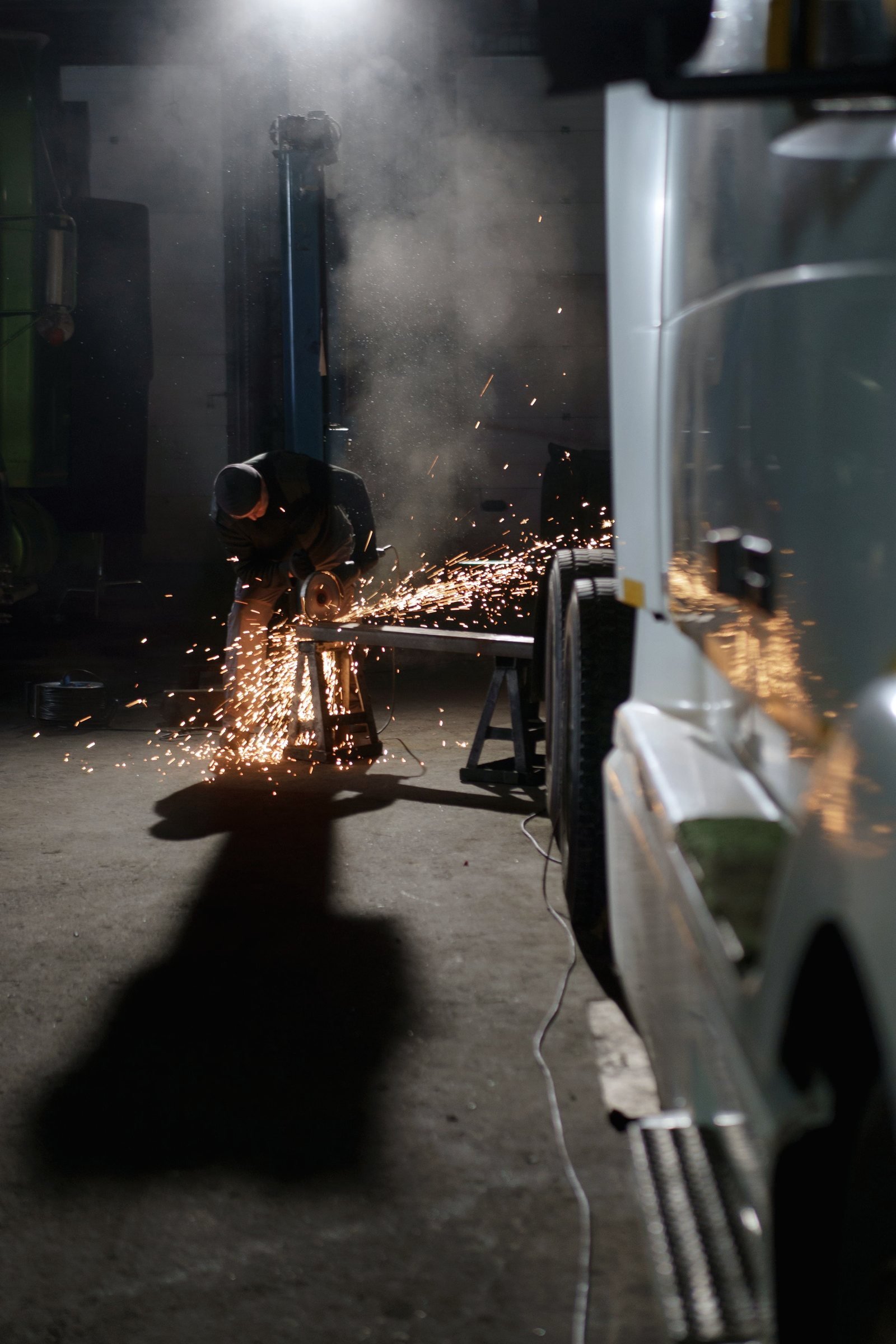 Sparks from an angle grinder during frame and body work in a shop bay