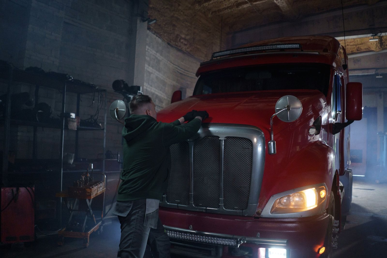 A technician working at the front of a tractor unit with the hood raised