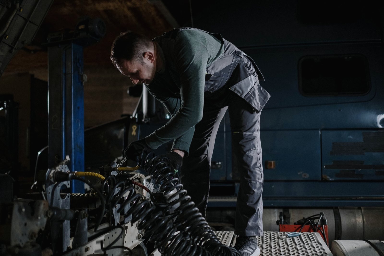 A technician working on suspension components and air lines at a truck frame